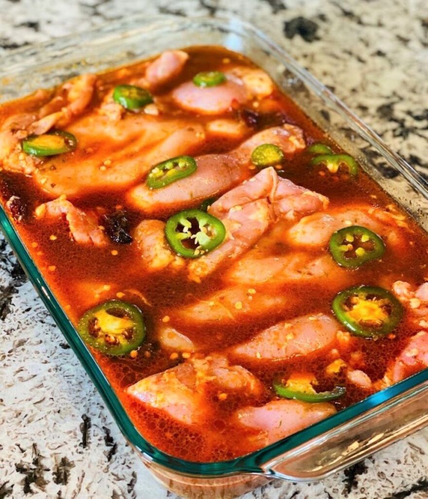 Beer marinated chicken breasts and jalapeno in glass baking dish 