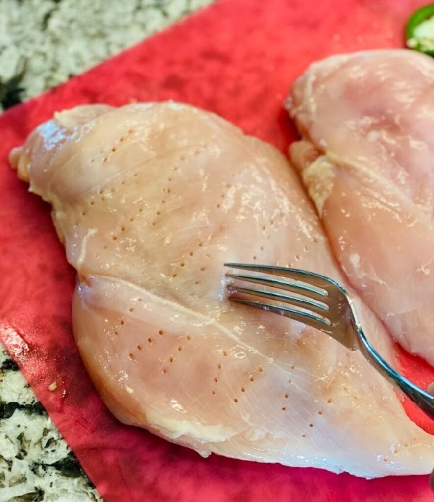 Piercing raw chicken breast with a fork